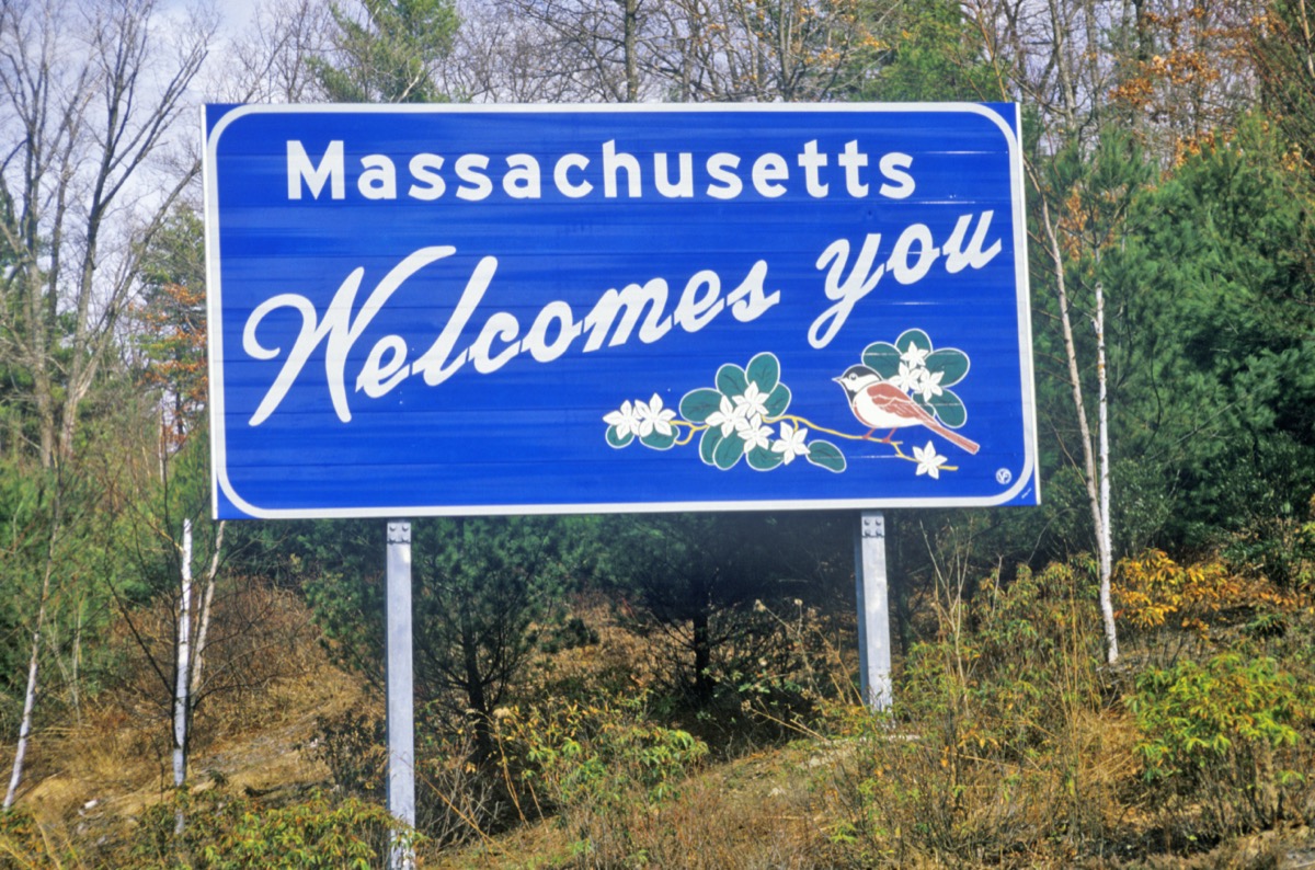 a blue "Massachusetts Welcomes You" sign in front of green trees