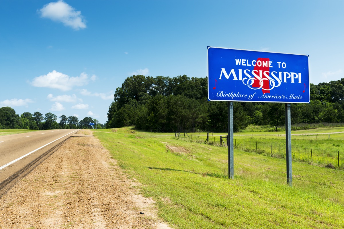 a blue "Welcome to Mississippi" sign off of a highway and within the grass