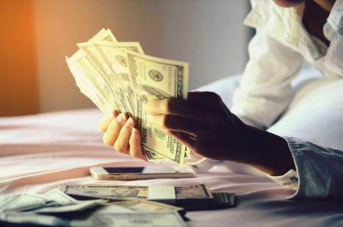 Woman holding a lot of money in bed