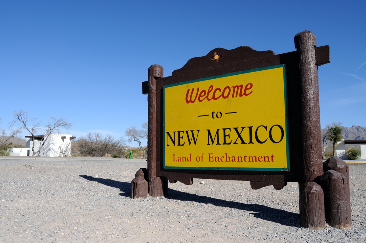 a "Welcome to New Mexico" sign with a yellow background and wooden border