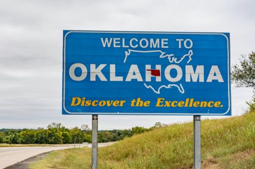a blue "Welcome to Oklahoma" sign off of a highway