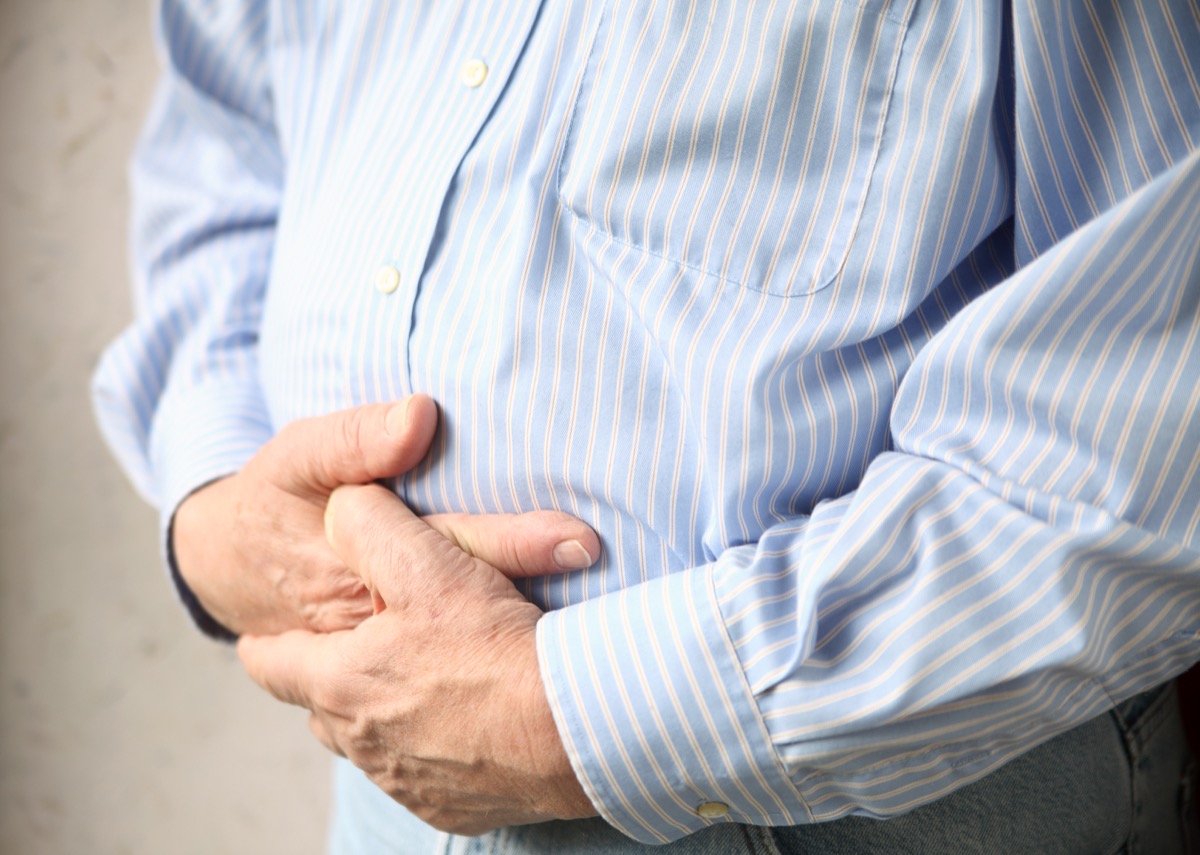 Man bloating holding his swollen stomach in discomfort