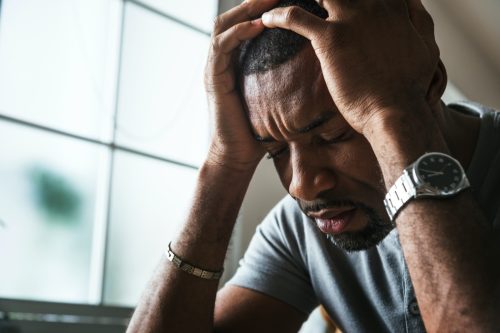 30-something black man with head in hands looking stressed or sad