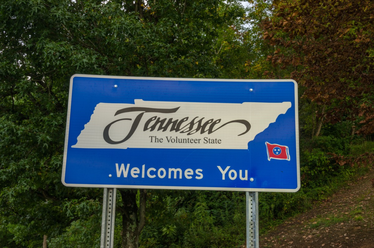 a blue "Tennessee Welcomes You" sign in front of green trees