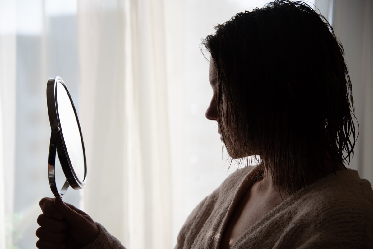 Woman looking at her eyebrows in a handheld mirror