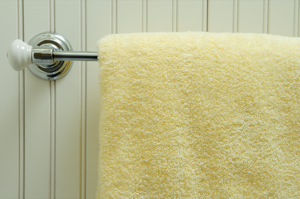 A soft bath towel hung on a chrome rack with bead-board background.