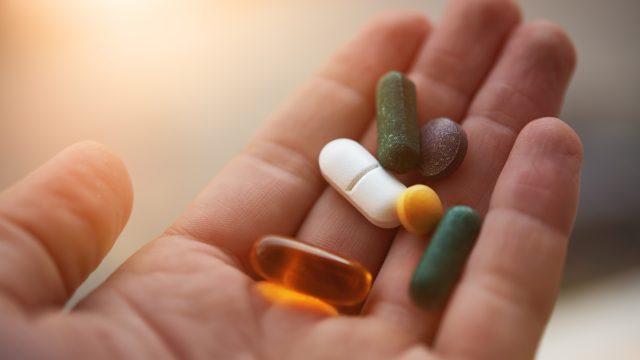 Assorted vitamin supplement pills resting in the palm of a hand