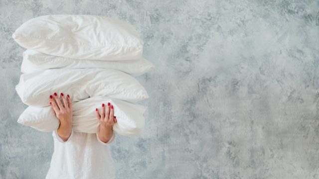 woman hold pile white pillows bedding sleeping