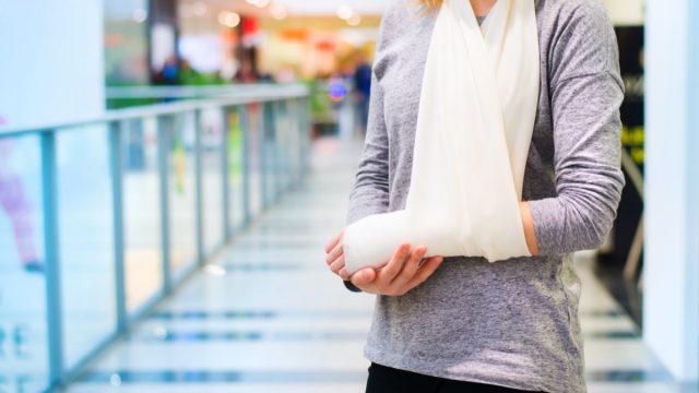 white woman with arm in a sling standing in a hospital or mall