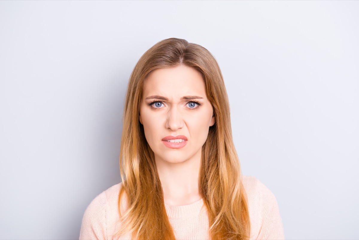 Close up portrait of funny confused puzzled unhappy upset sad uncertain unsure beautiful pretty charming grimacing woman with long blonde hairdo isolated on gray background opy-space