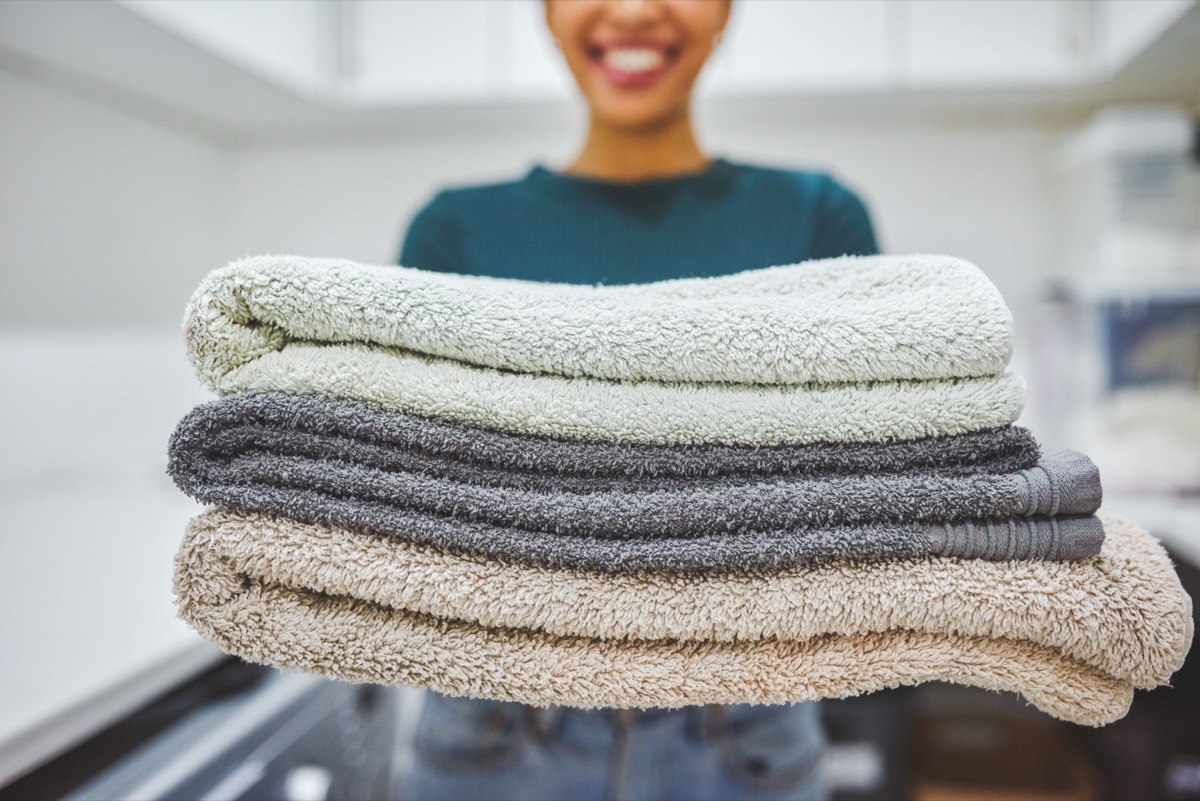 Closeup shot of a woman holding a stack of towels at home