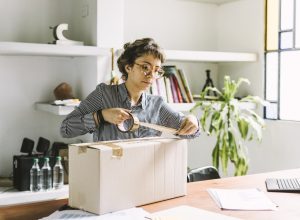 Young freelance woman sending a package to client.