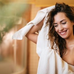 Young beautiful woman using towel and drying her hair in the bathroom.