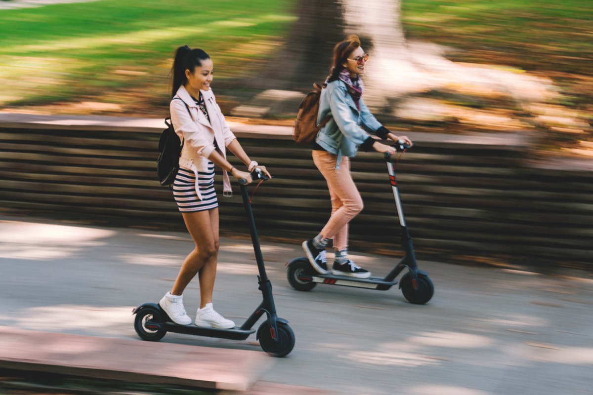 Two women riding motor scooters