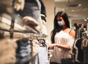 A young woman wearing a face mask shopping in a retail clothing store amid the coronavirus pandemic