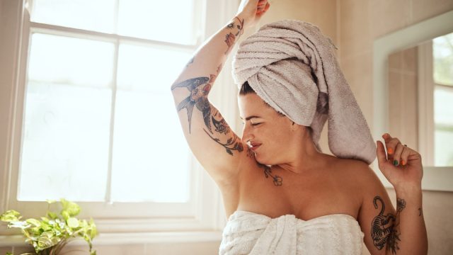 Shot of an attractive young woman smelling her armpits during her morning beauty routine