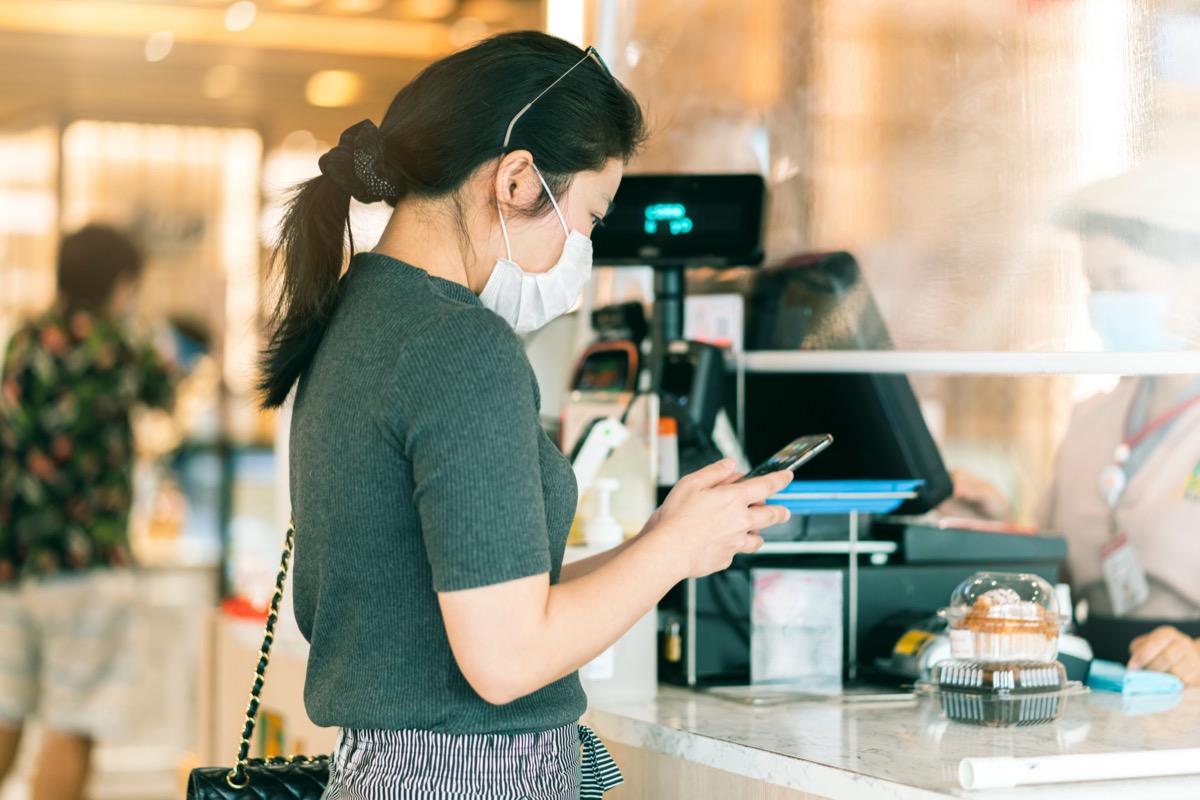 young asian woman using cell phone at checkout counter