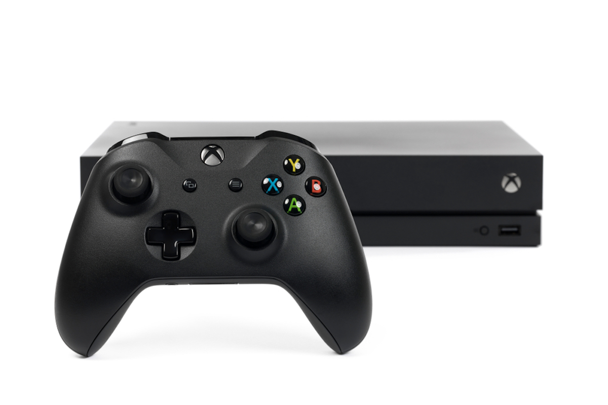 A close-up studio shot of a Microsoft XBOX One X controller and system on a white background.