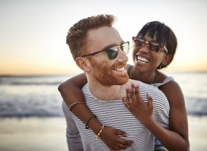 A young heterosexual couple hugging on the beach at sunset.