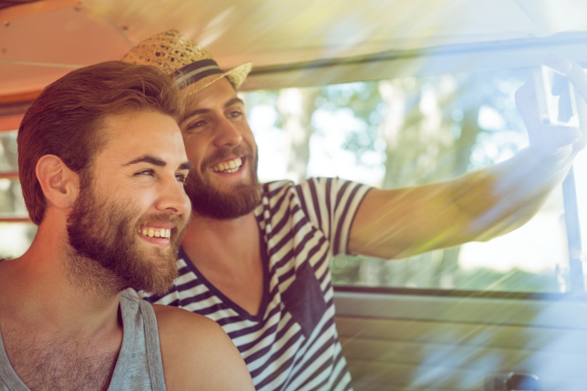 young white male couple smiling and taking selfie in a van