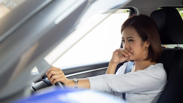 Young Asian woman hold her nose because of bad smell in car