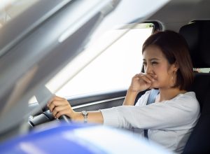 Young Asian woman hold her nose because of bad smell in car