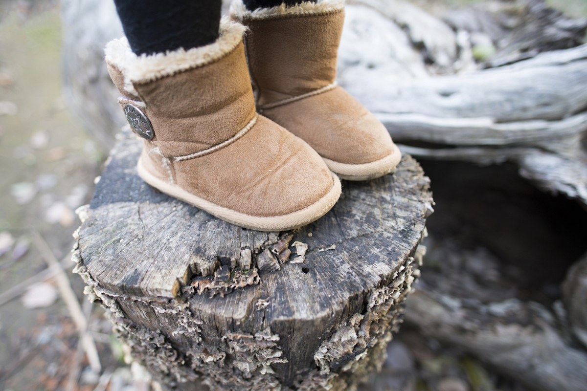 closeup of child's winter boots standing on top of the fallen tree