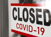 A sign hanging on a businesses door telling customers they are closed due to COVID-19