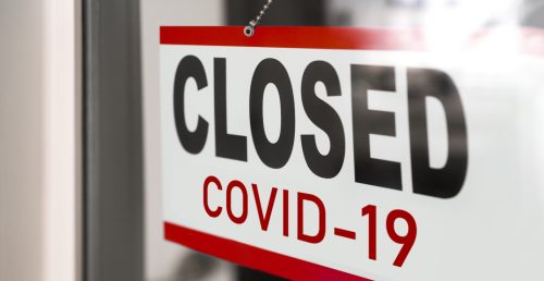 A sign hanging on a businesses door telling customers they are closed due to COVID-19
