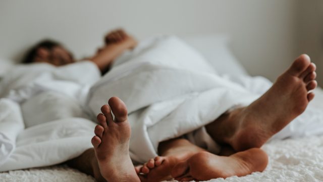 A couple's feet next to each other in bed.