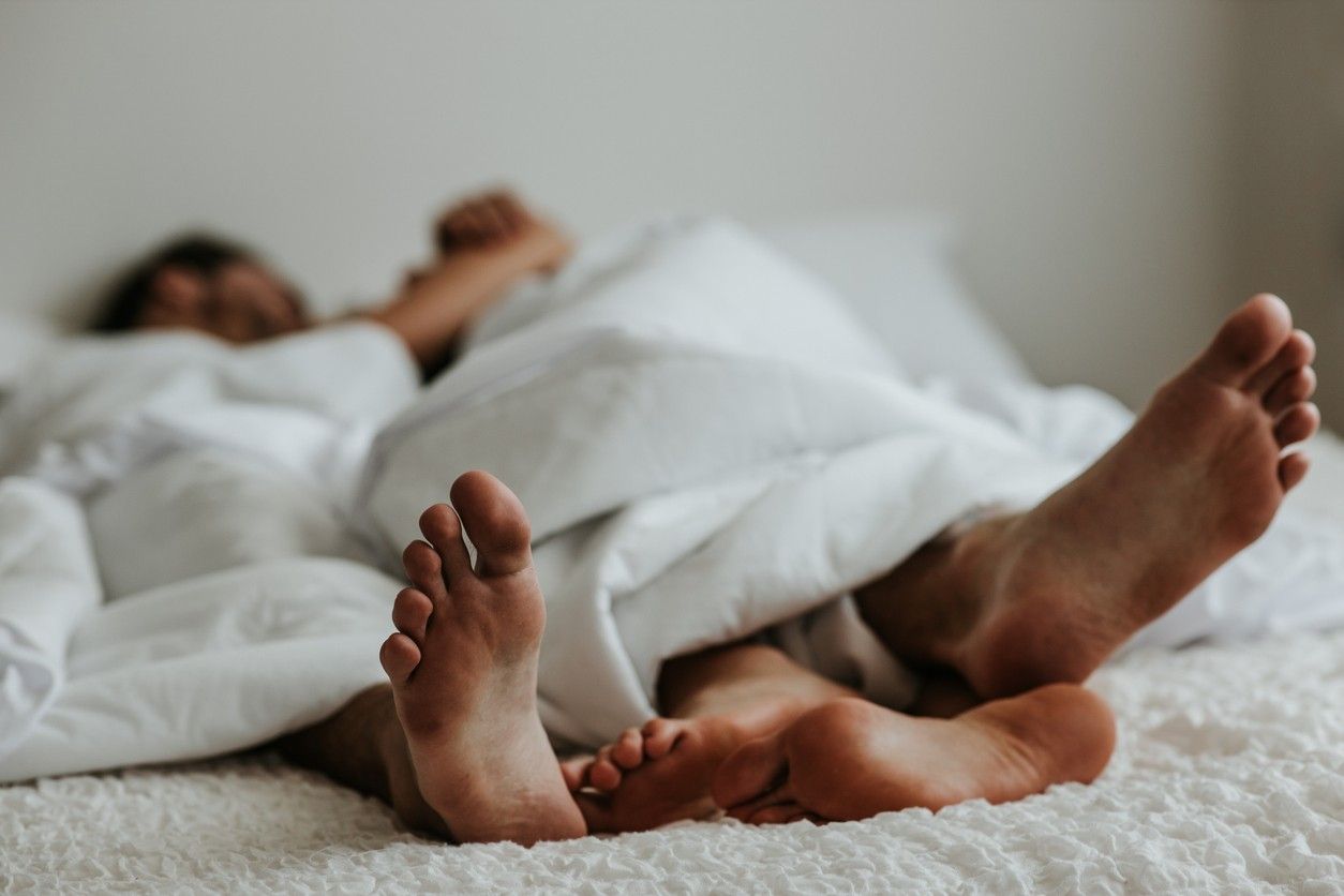 A couple's feet next to each other in bed.