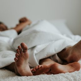 A couple's feet next to each other in bed.