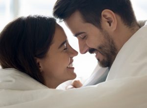 happy couple wrapped in duvet, smiling at each other