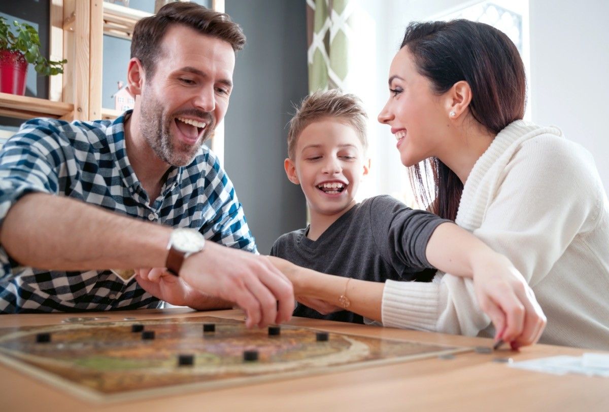 mother, father, and son smiling while playing a board game