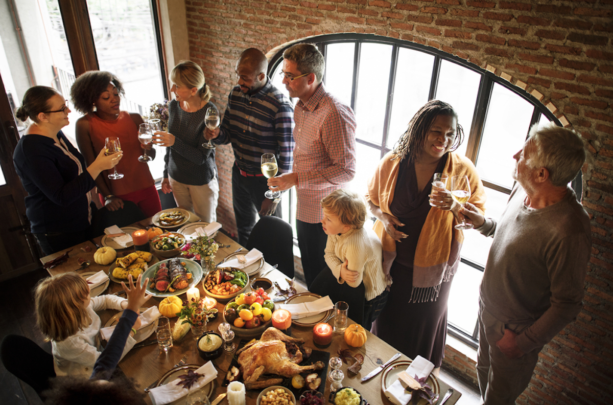 adults and children gather around a thanksgiving table inside