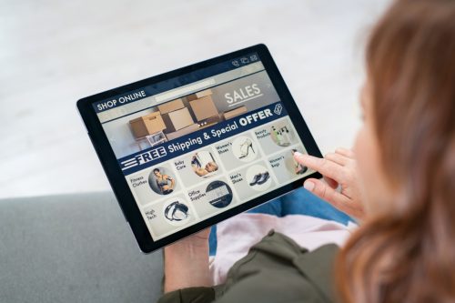 woman holding a tablet that shows sales and free shipping on a online shopping site