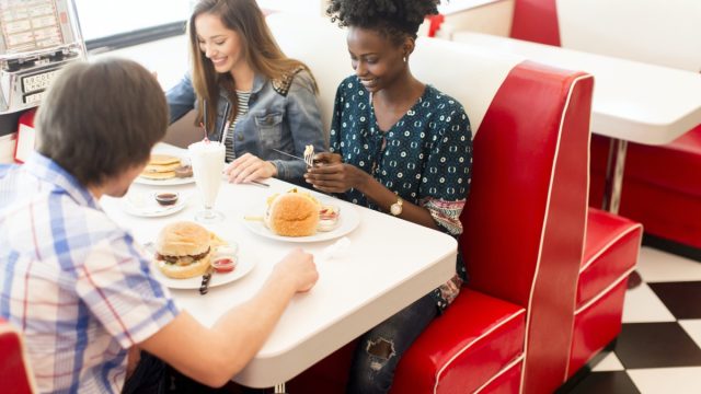 young multiethnic friend group eating hamburgers at diner
