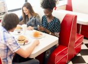 young multiethnic friend group eating hamburgers at diner