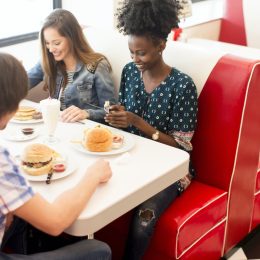 young multiethnic friend group eating hamburgers at diner