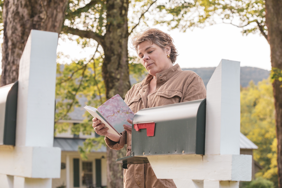 middle aged white woman Woman Reading a greeting card at the mailbox