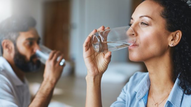 Shot of a couple drinking glasses of water together at home
