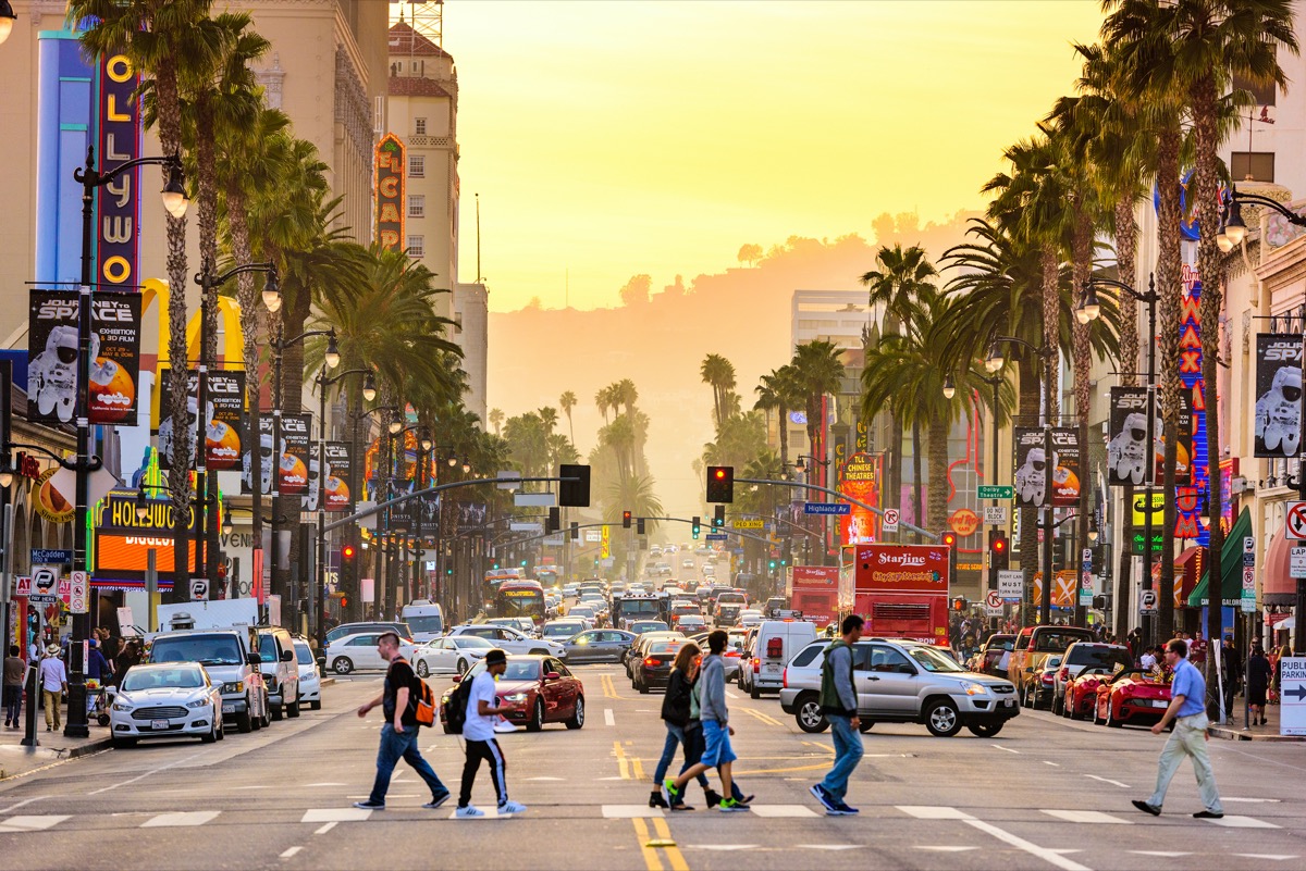 pedestrians walking across the street on Hollywood Boulevard in Los Angeles, California at dusk