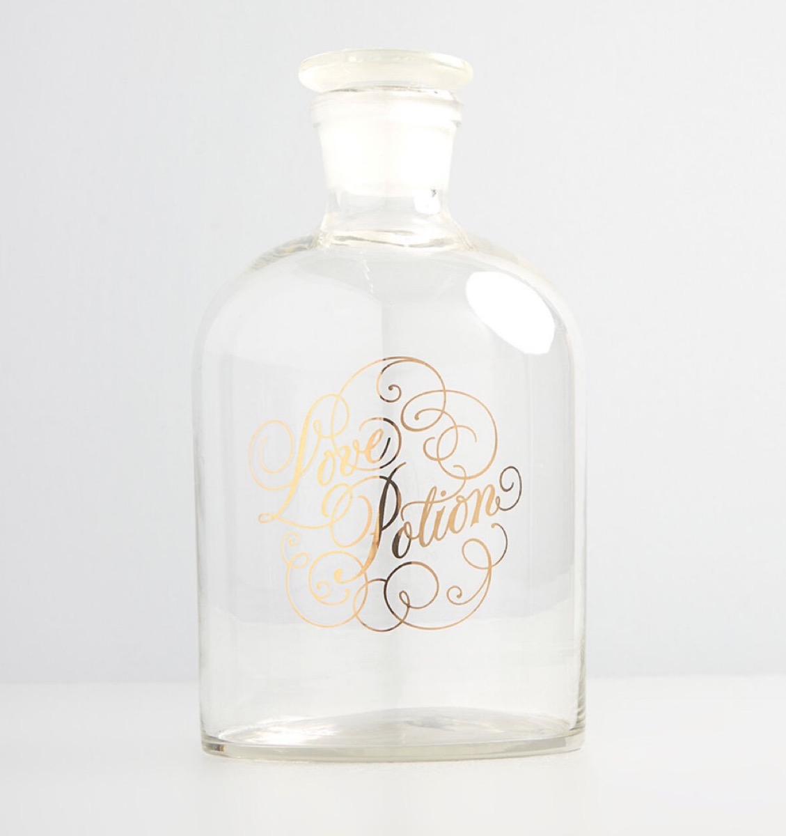 clear decanter with "love potion" written on it in gold