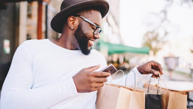young black man looking at shopping bags looking happy
