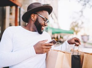 young black man looking at shopping bags looking happy
