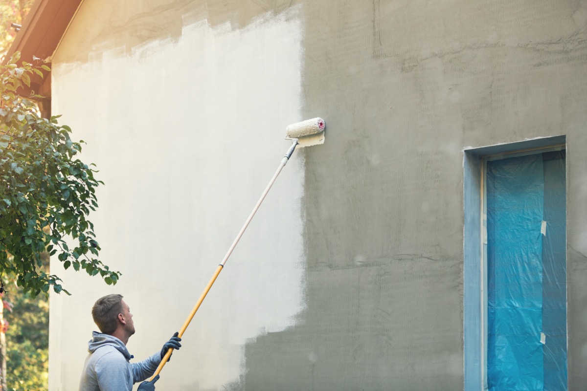 man painting home exterior white