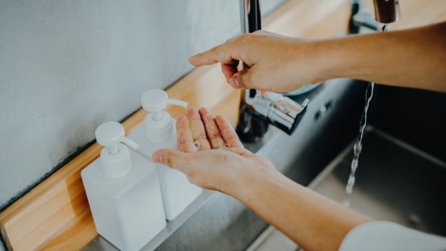 Cropped shot of a man dispensing soap before washing his hands in the sink