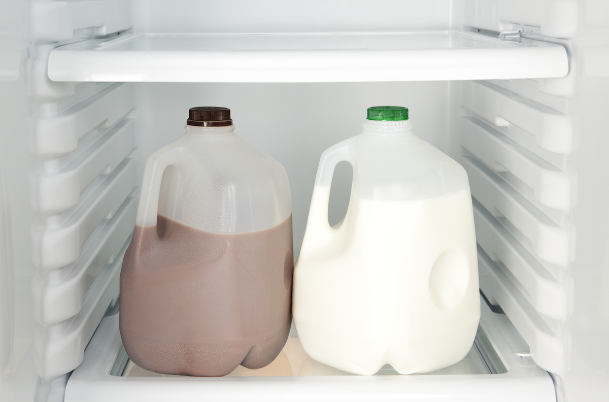 Open refrigerator with chocolate and white milk.