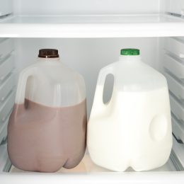 Open refrigerator with chocolate and white milk.