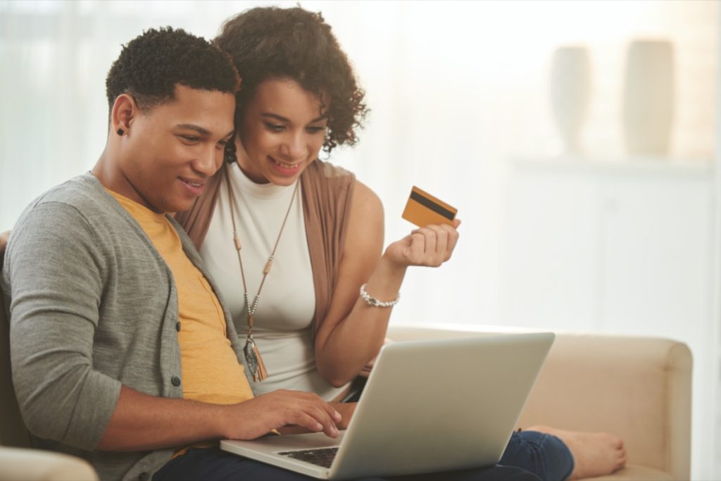 Latin-American woman holding a card and Latin-American man looking at a computer